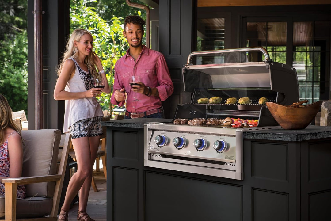 Built-in gas grill, Broil King Regal series, luxury outdoor kitchen, couple entertaining with food grilling on open hood