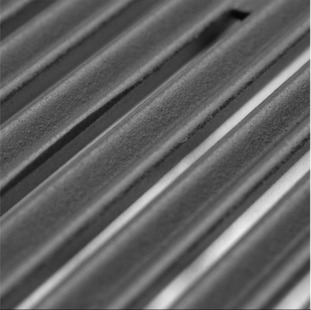Close-up of cast stainless steel grill cooking grates with textured surface and deep grooves.