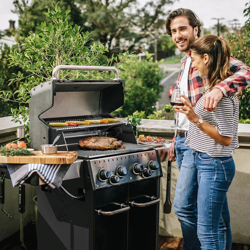 Grill, Broil King, Baron, lifestyle couple grilling on patio with open lid and food on grates