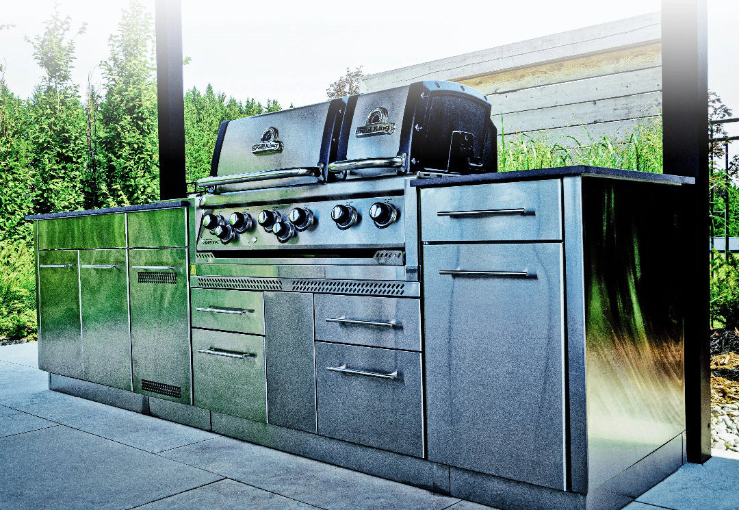 Stainless steel outdoor kitchen with grill and cabinets in a garden setting