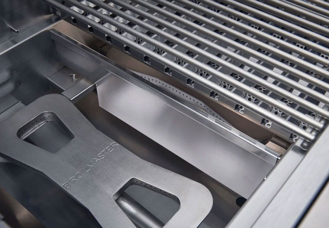 Broilmaster B-Series BSB324NLP 32-inch 4-burner stainless steel propane grill head interior close-up showing Broilmaster-engraved heat diffuser/flame tamer, stainless cooking grates and grease drip tray