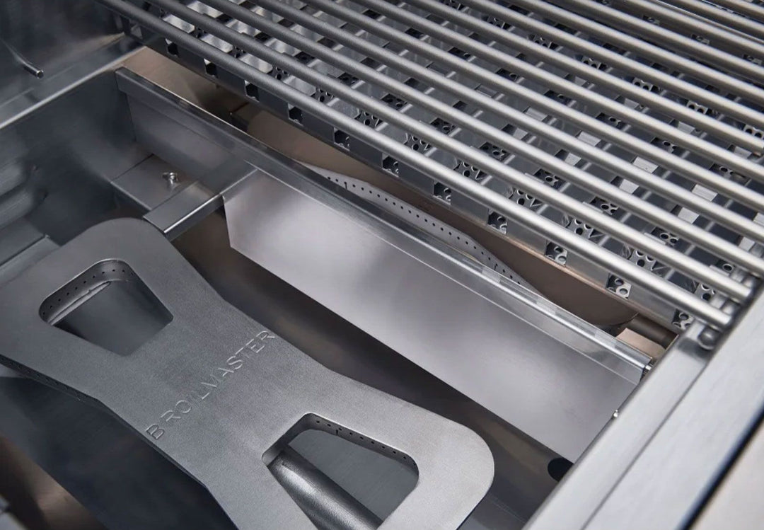 Broilmaster B-Series Basic Edition BSB253NLN 3‑burner 25‑inch natural gas grill interior close-up showing stainless steel cooking grates, Broilmaster‑stamped stainless heat deflector/flavorizer and grease tray