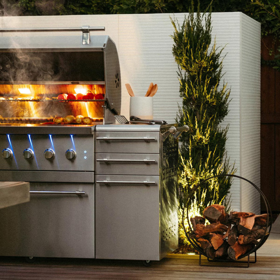 American Made Grills Encore 54" freestanding natural gas grill with LED-lit knobs, open hood, and grilling in progress