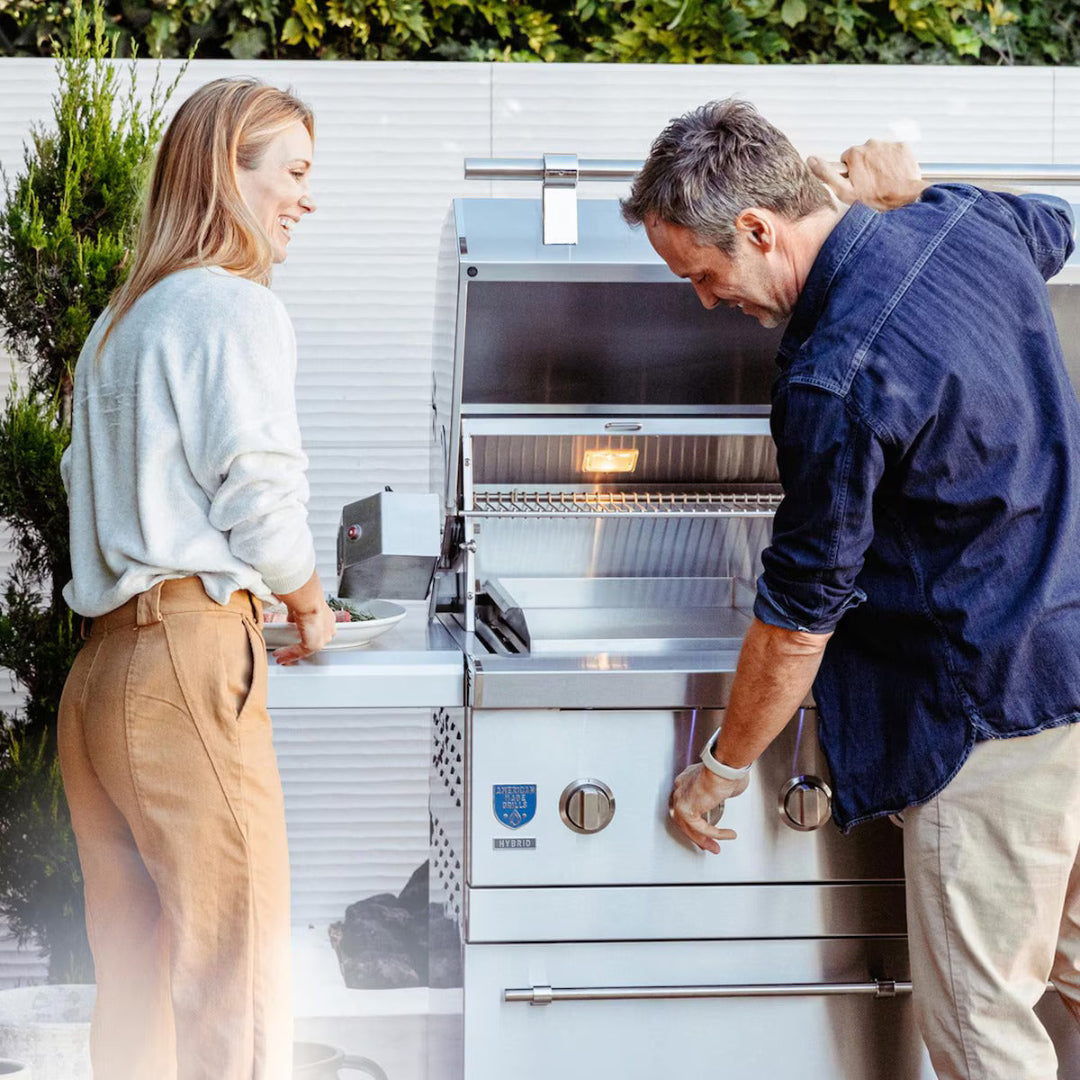 Couple grilling with American Made Grills Encore 54" freestanding natural gas grill featuring LED knobs and storage base