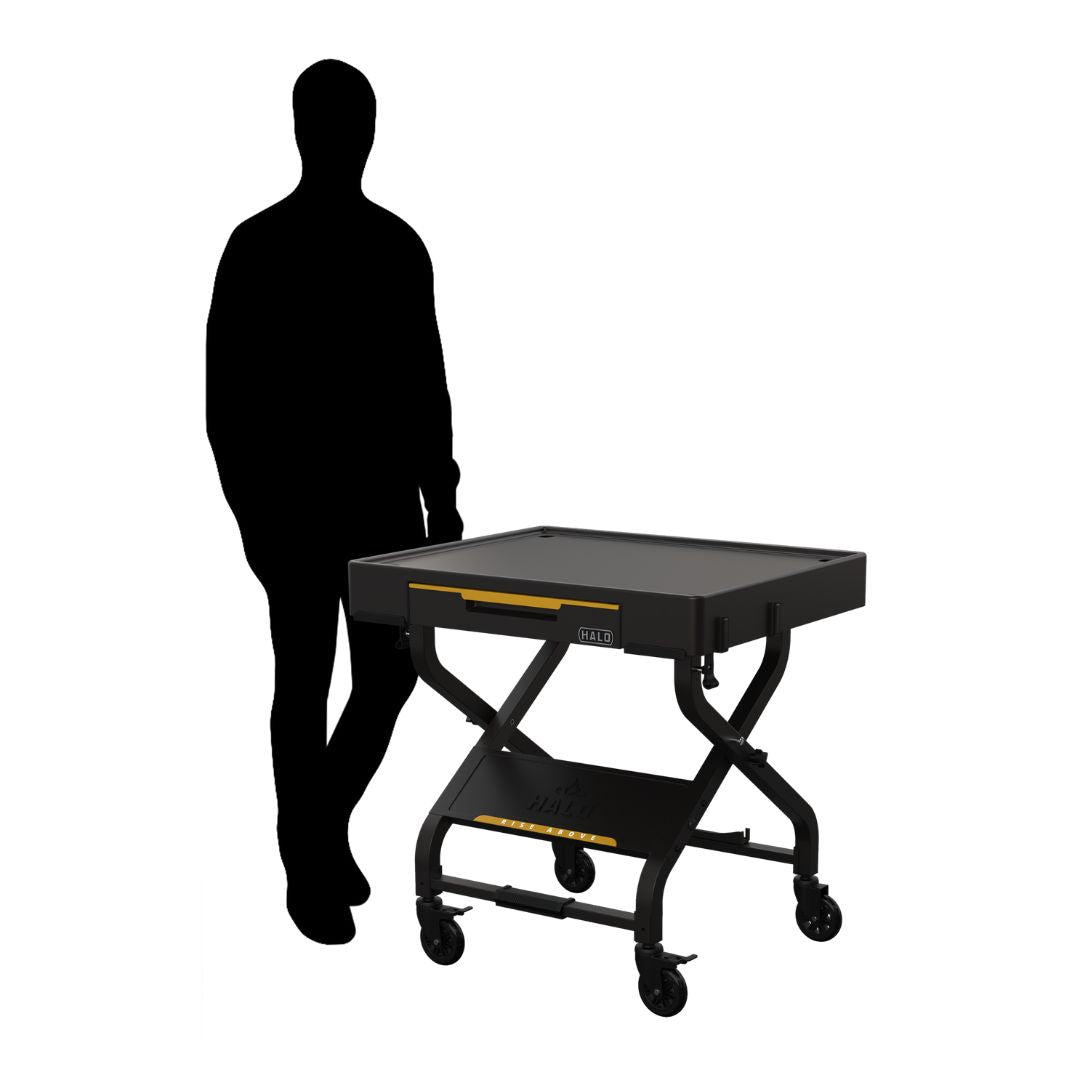 HALO HO-1006-XNA collapsible black outdoor countertop prep cart with drop-down drawer, magnetic hooks, propane tank bracket and locking casters, shown with silhouette for scale.