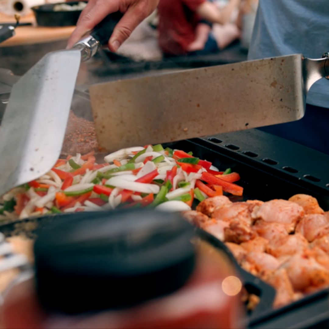 HALO Elite 4B Griddle HZ-1001-XNA flat-top griddle close-up cooking bell peppers, onions and seasoned chicken with metal spatulas