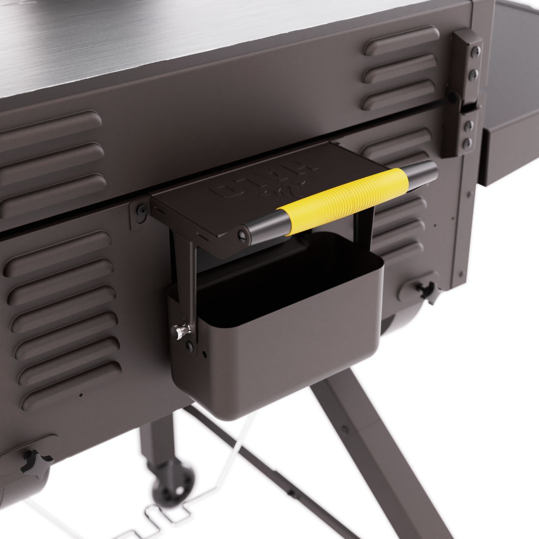 HALO Elite 2B Griddle HZ-1003-XNA close-up of XL rear grease trough with yellow-handled utensil squeegee on vented steel body and caster leg