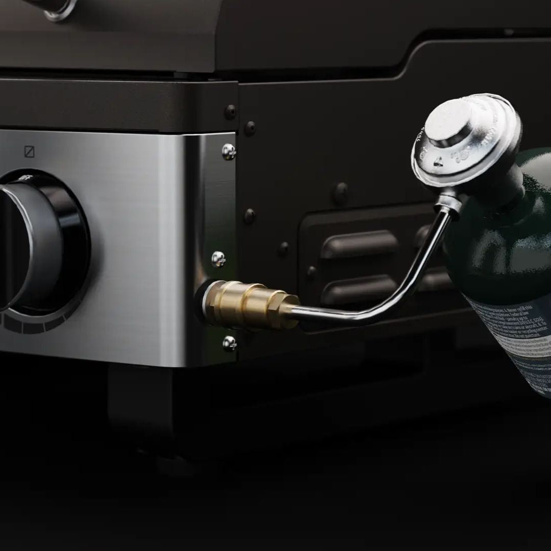 HALO Elite 1B Griddle (HZ-1007-ANA) close-up of stainless-steel control panel and knob with brass propane quick‑connect and regulator hose attached to a green propane cylinder on a black countertop griddle