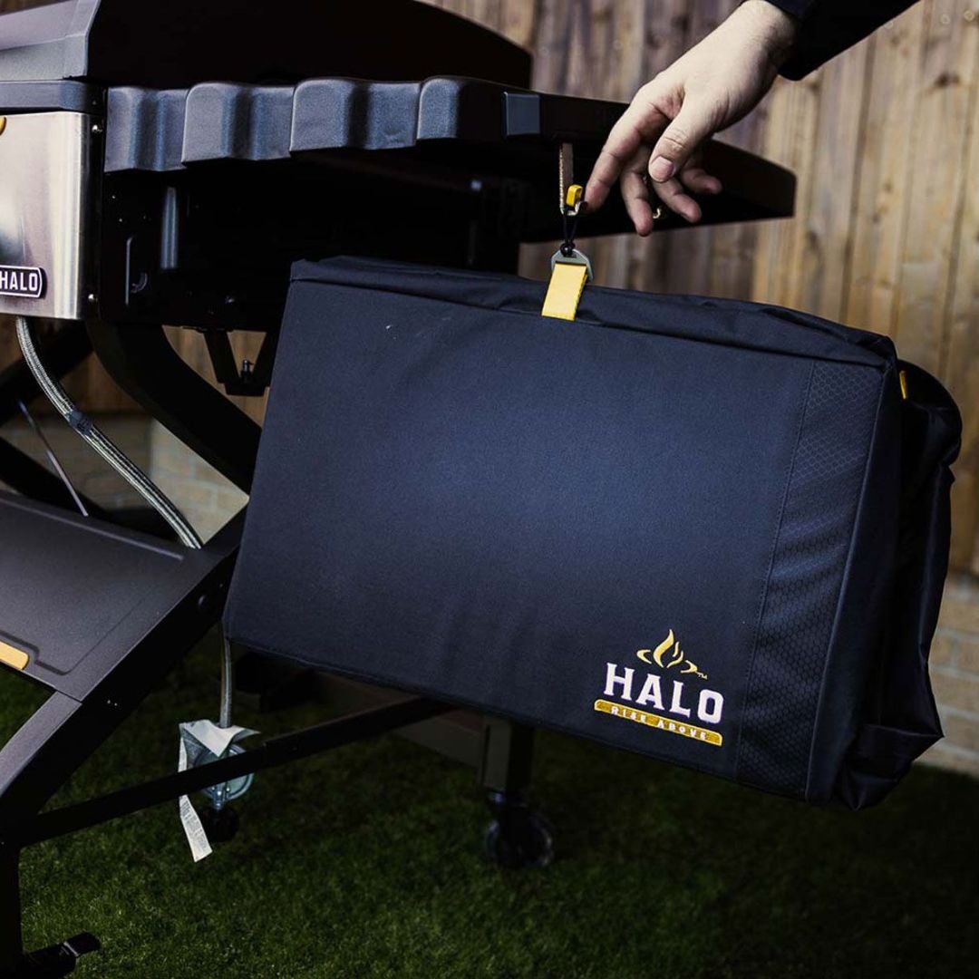 HALO Elite 4B griddle cover HZ-5001 — black protective cover with yellow strap and embroidered HALO logo hanging from grill side table