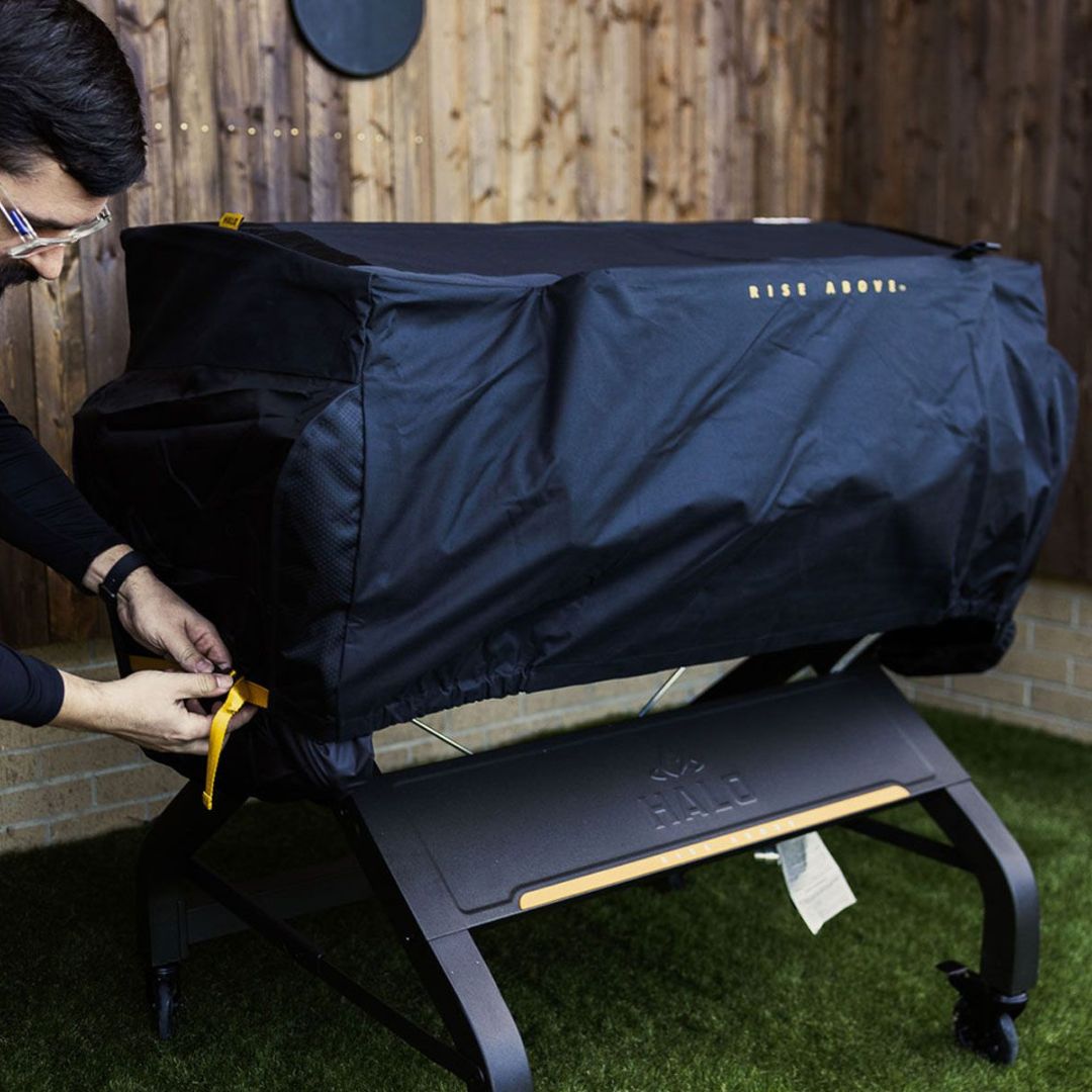 HALO Elite 4B Griddle Cover HZ-5001 — black PVC-coated protective cover with elasticized hem and yellow tie strap being fastened on griddle