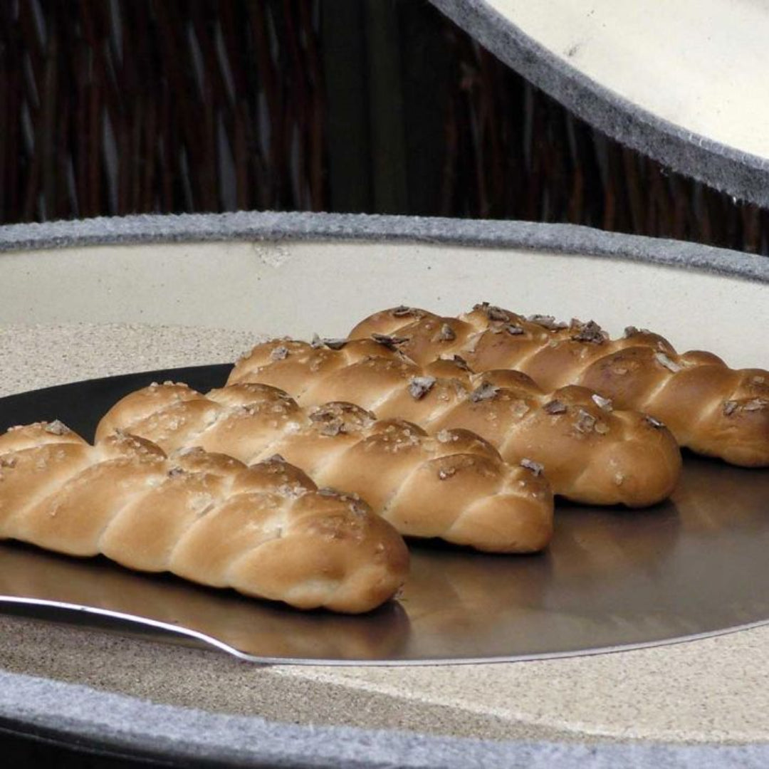round stainless steel pizza and bread baking peel PG00351 holding braided artisan bread rolls in wood-fired outdoor pizza oven