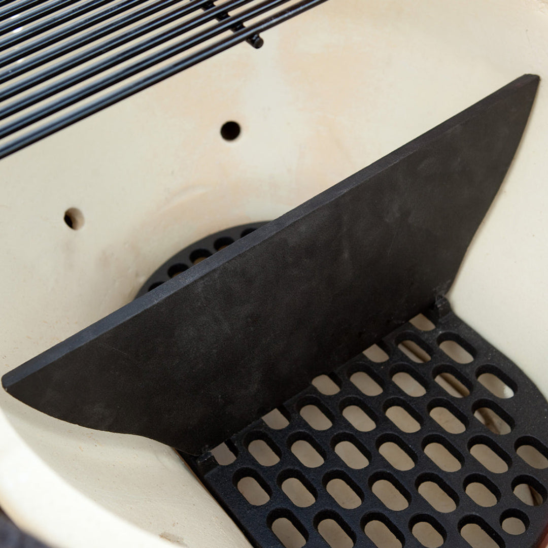 Primo cast-iron firebox divider installed on firebox grate inside Primo kamado ceramic grill — heavy-duty cast-iron heat deflector by Vine & Flame