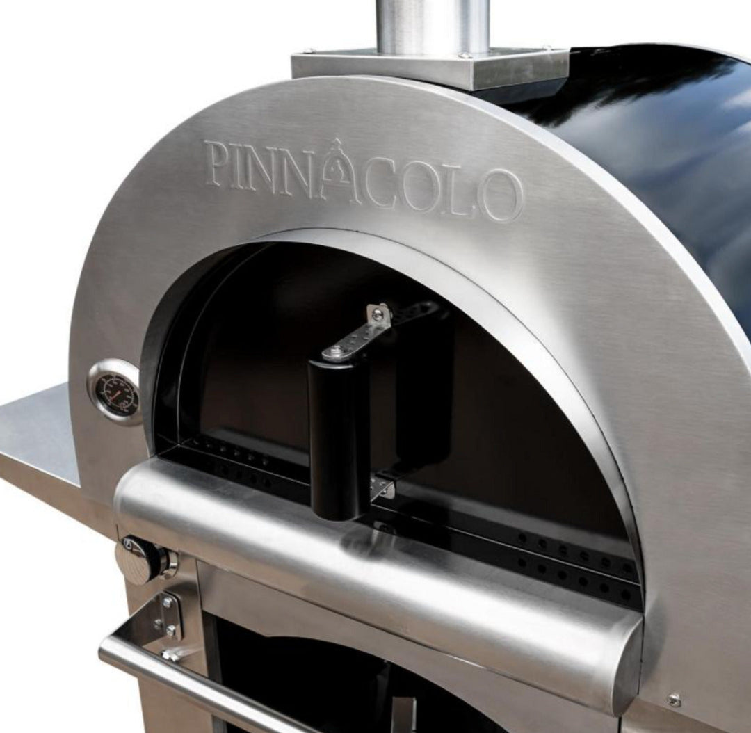 Pinnacolo stainless steel outdoor pizza oven front with arched opening, built-in temperature gauge, black door handle, gas control knob and stainless chimney