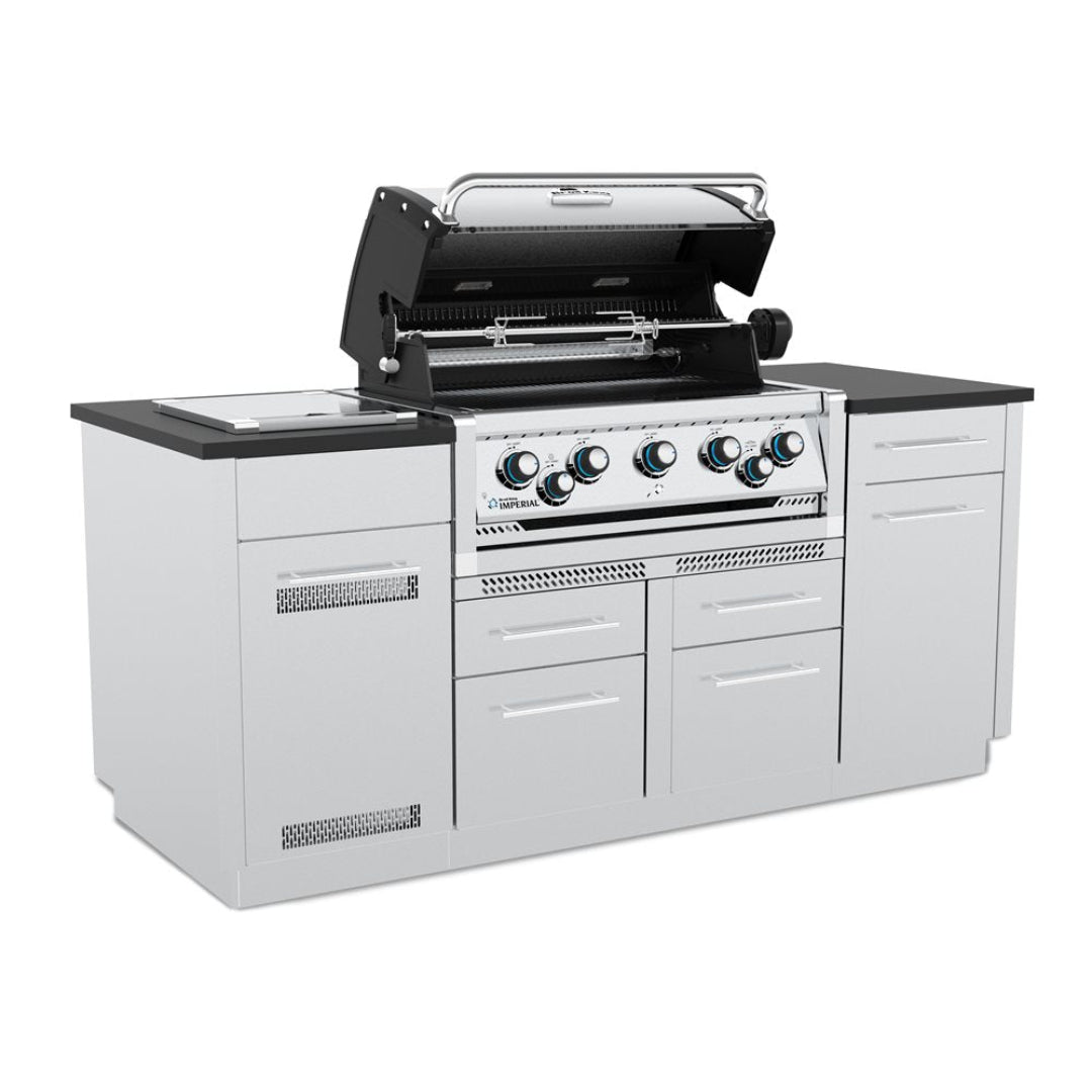 Imperial S-590i built-in five-burner stainless steel gas grill with rotisserie and side burner, open hood, integrated into white outdoor kitchen island with black countertop and storage drawers