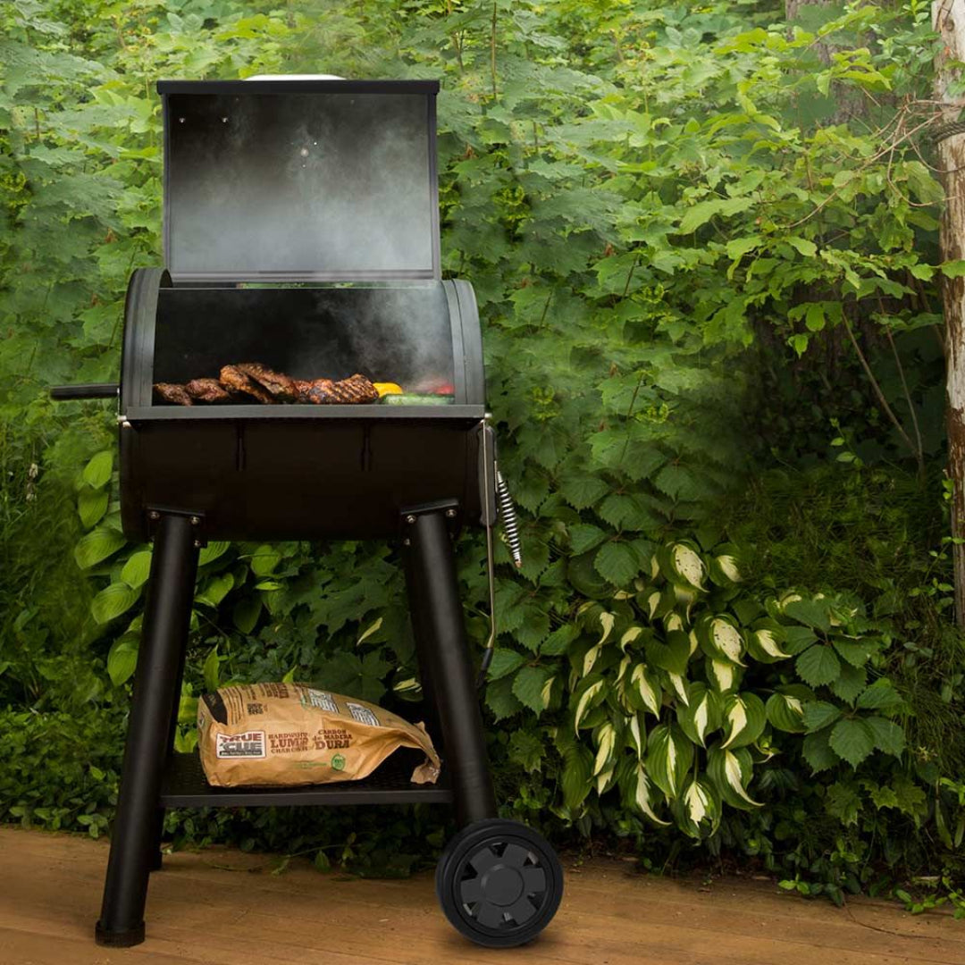 Charcoal grill, Broil King, Smoke Series, freestanding with wheels, open lid grilling meats, set in lush green backyard
