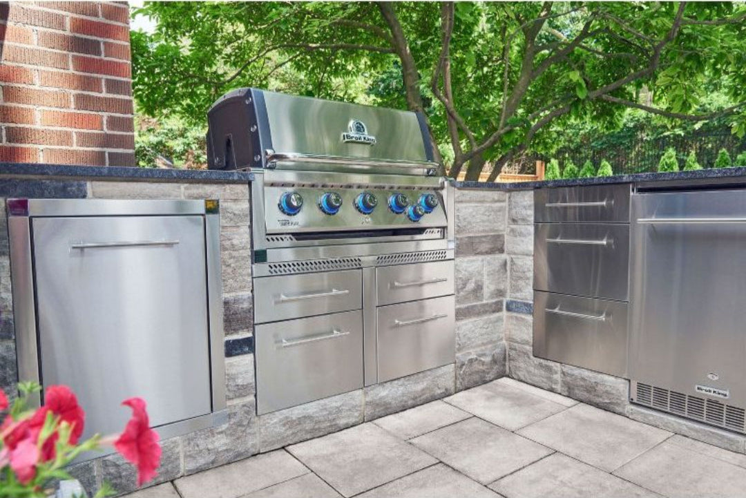 Broil King Imperial built-in grill in outdoor kitchen with illuminated knobs and stainless steel cabinetry.
