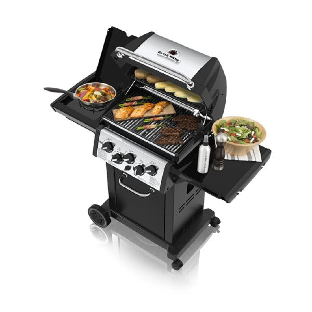 Freestanding Grill, Broil King, Baron Series, full grill setup with food, vegetables, meat, and salad on side shelves