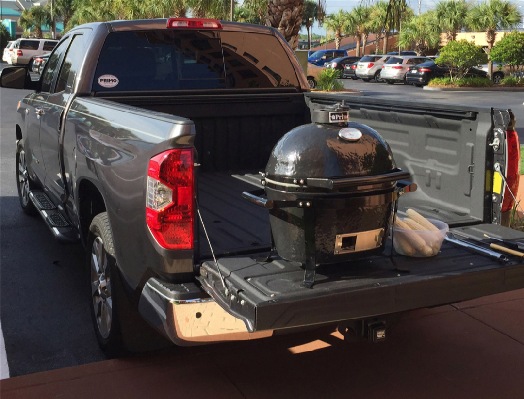 Primo Go portable ceramic kamado charcoal grill on pickup truck tailgate with corn and tongs — tailgating and camping BBQ, Vine and Flame