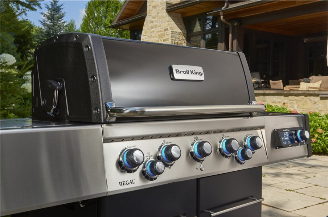 Broil King Regal Q 590 stainless steel multi-burner gas grill with blue-illuminated control knobs and digital temperature display for outdoor patio propane barbecue