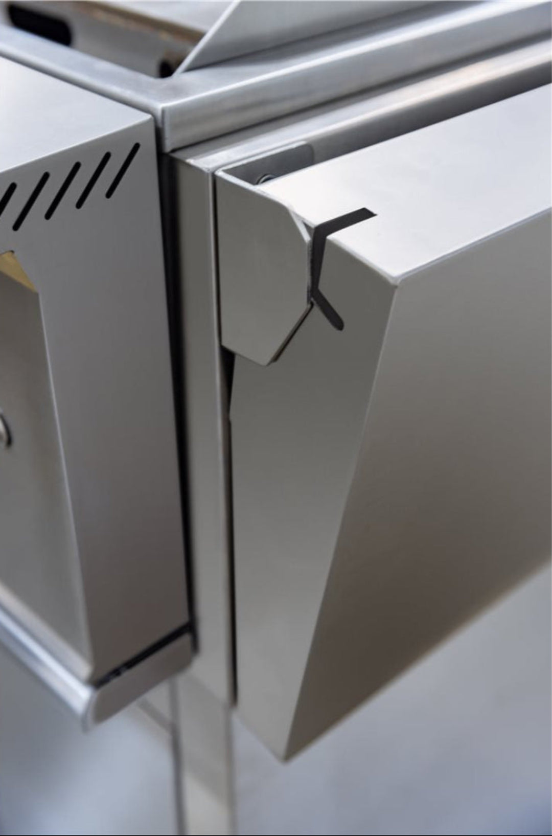 Stainless steel 30-inch outdoor grill cart hinge and latch close-up on modular outdoor kitchen cabinet door