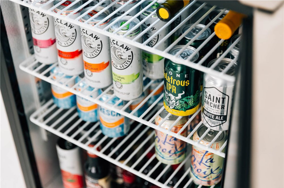 Vine & Flame 125-TF-RFR-24D 24-inch compact beverage refrigerator interior with adjustable white wire shelves stocked with canned seltzers and beer