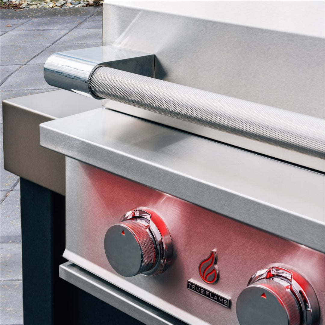 True Flame stainless steel built-in gas grill front panel close-up with knurled stainless-steel control knobs, textured roll-bar handle and True Flame logo