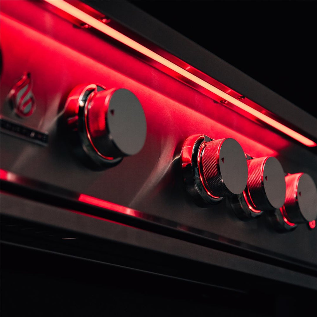 Trueflame stainless steel gas grill control panel close-up with knurled chrome burner knobs and red LED accent lighting for built-in outdoor kitchen