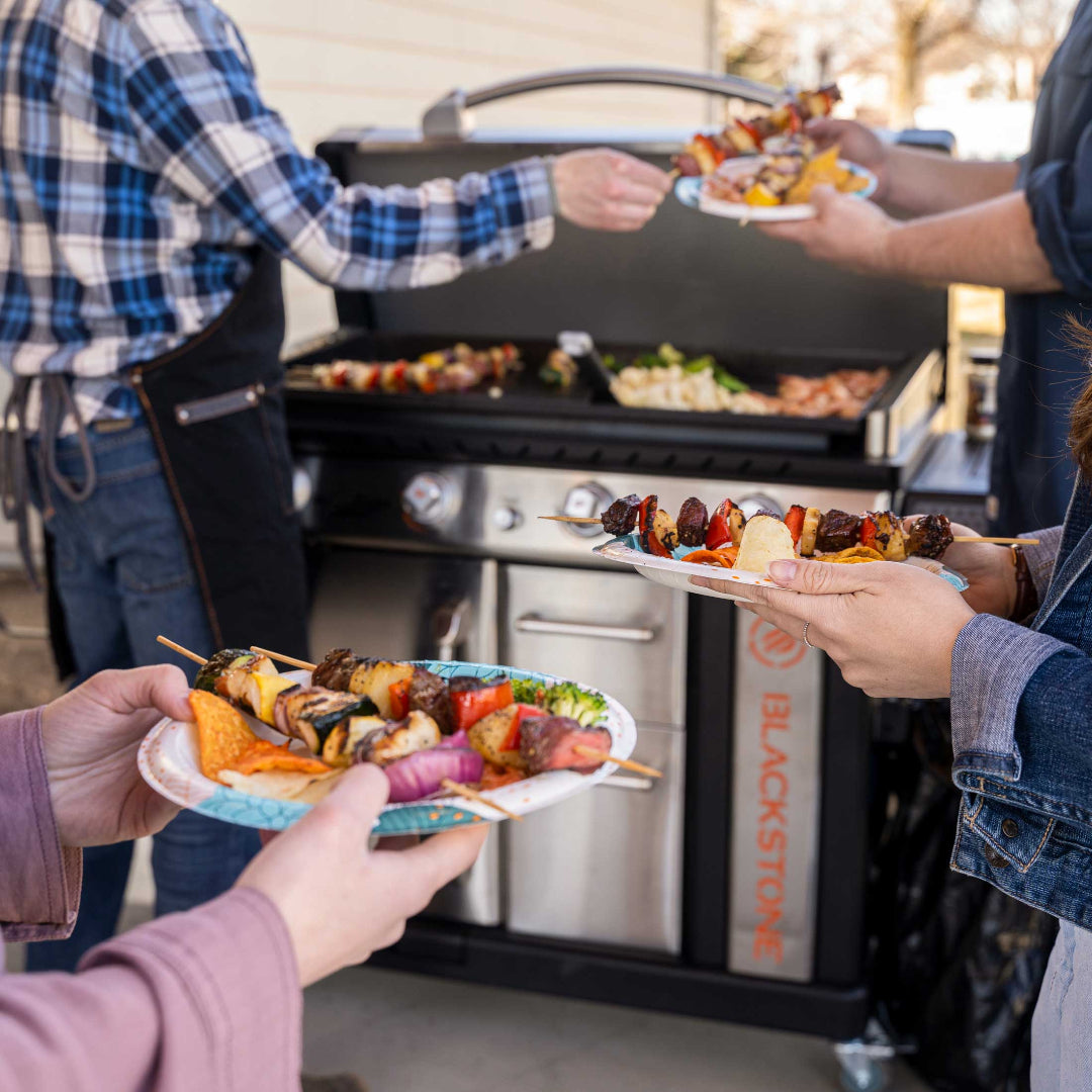 Blackstone 36-inch Patio Pro griddle on rolling cart with stainless steel cabinet grilling skewered kebabs and vegetables at backyard cookout, outdoor propane flat-top griddle, Vine & Flame
