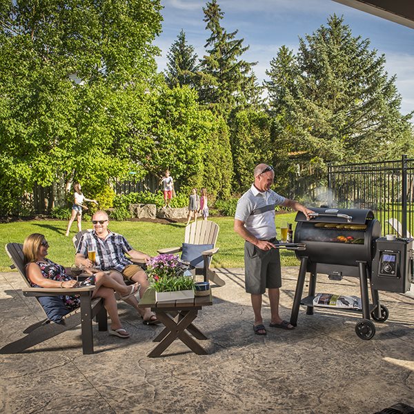 Pellet grill, Broil King, Regal series, in use at backyard gathering with friends, digital controls visible