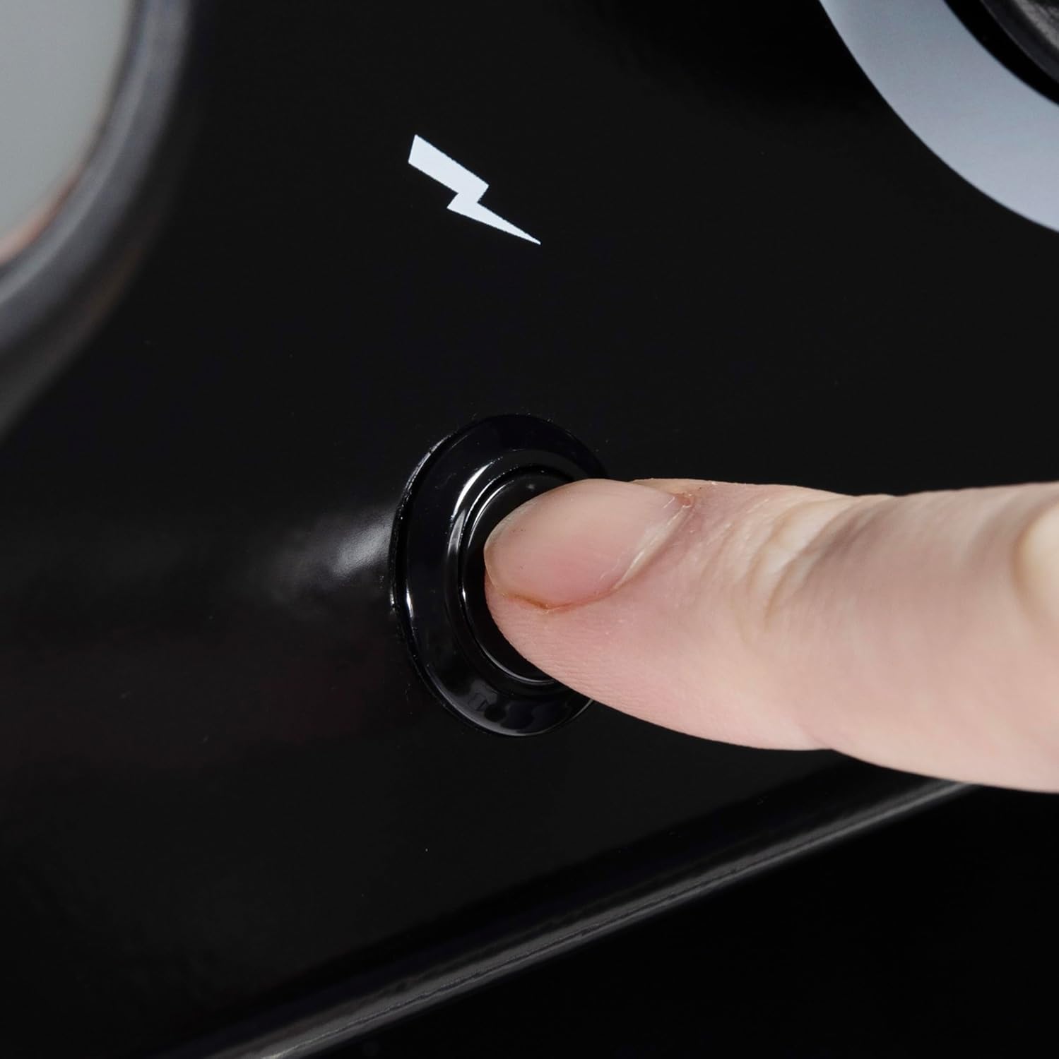 Ignition button close-up, Broil King Crown series, showing finger pressing electric spark igniter on propane grill.