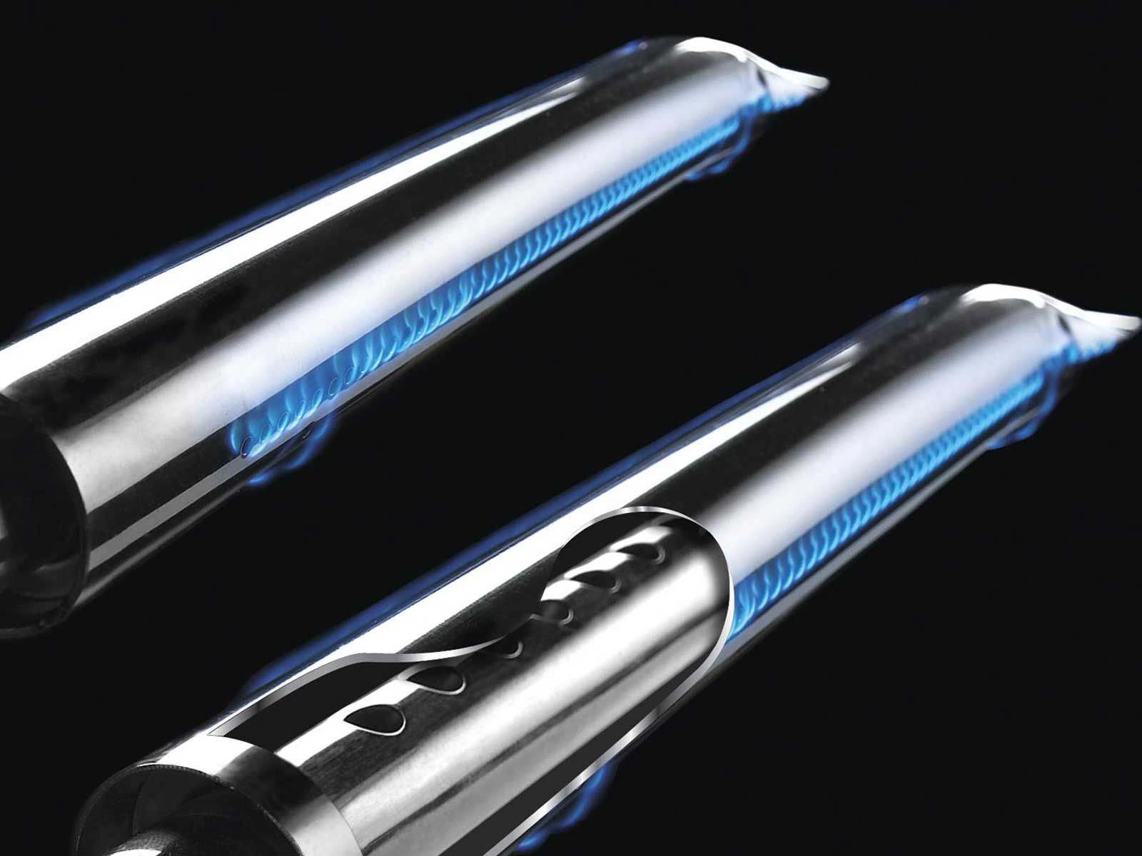 Close-up of dual Broil King Regal stainless steel tube burners with blue flame jets on black background