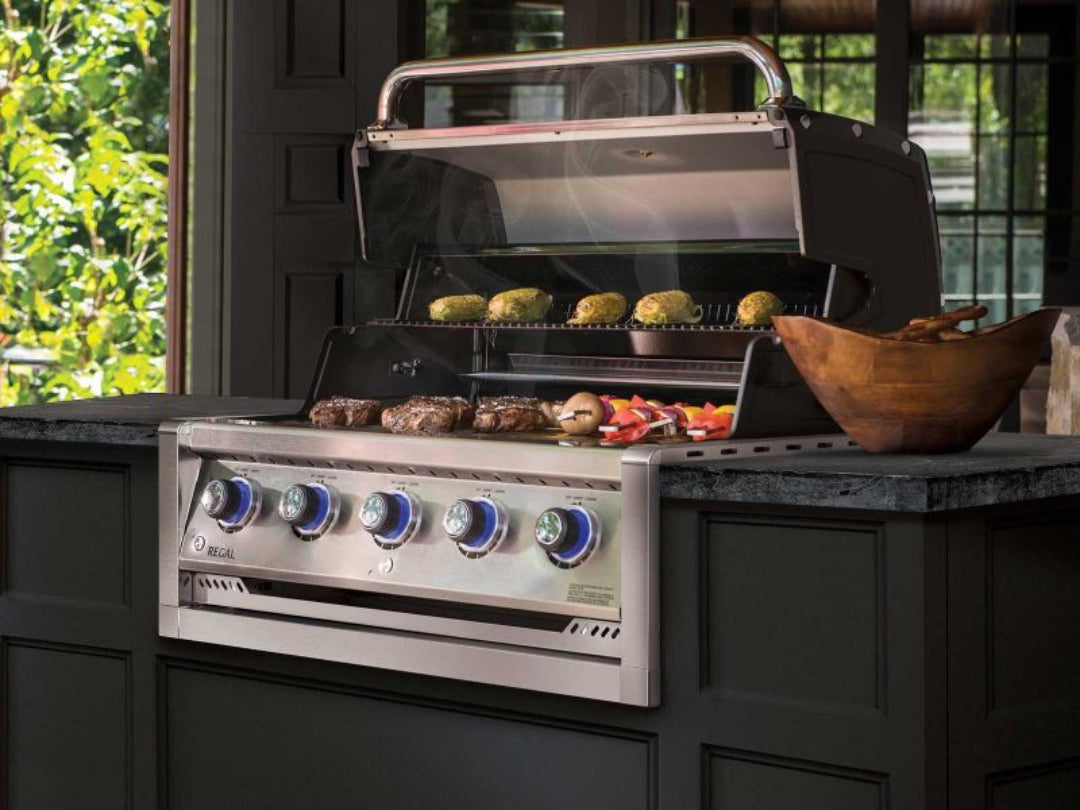Built-in gas grill, Broil King Regal, five-burner, blue LED knobs, outdoor kitchen, open hood with food grilling
