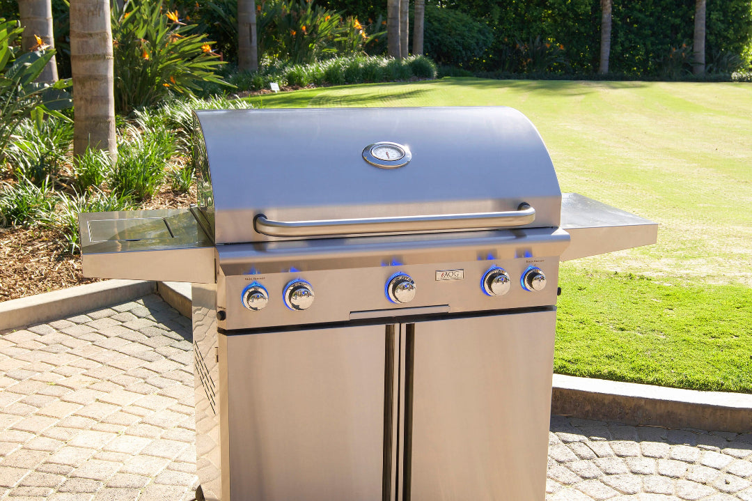 AOG 36PCL 3622 L-Series 36-inch stainless steel portable 4-burner gas grill on cart with side shelves, built-in lid thermometer and blue LED illuminated control knobs, outdoor patio lifestyle