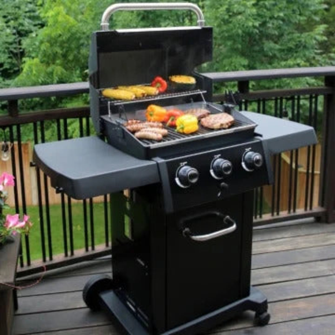 Grill, Broil King, Crown Series, freestanding propane grill with 3 burners and food on grates, on wooden deck