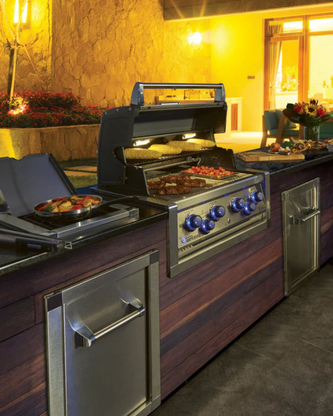 Built-in Broil King Imperial S690i natural gas grill with blue-lit knobs in luxury outdoor kitchen setting