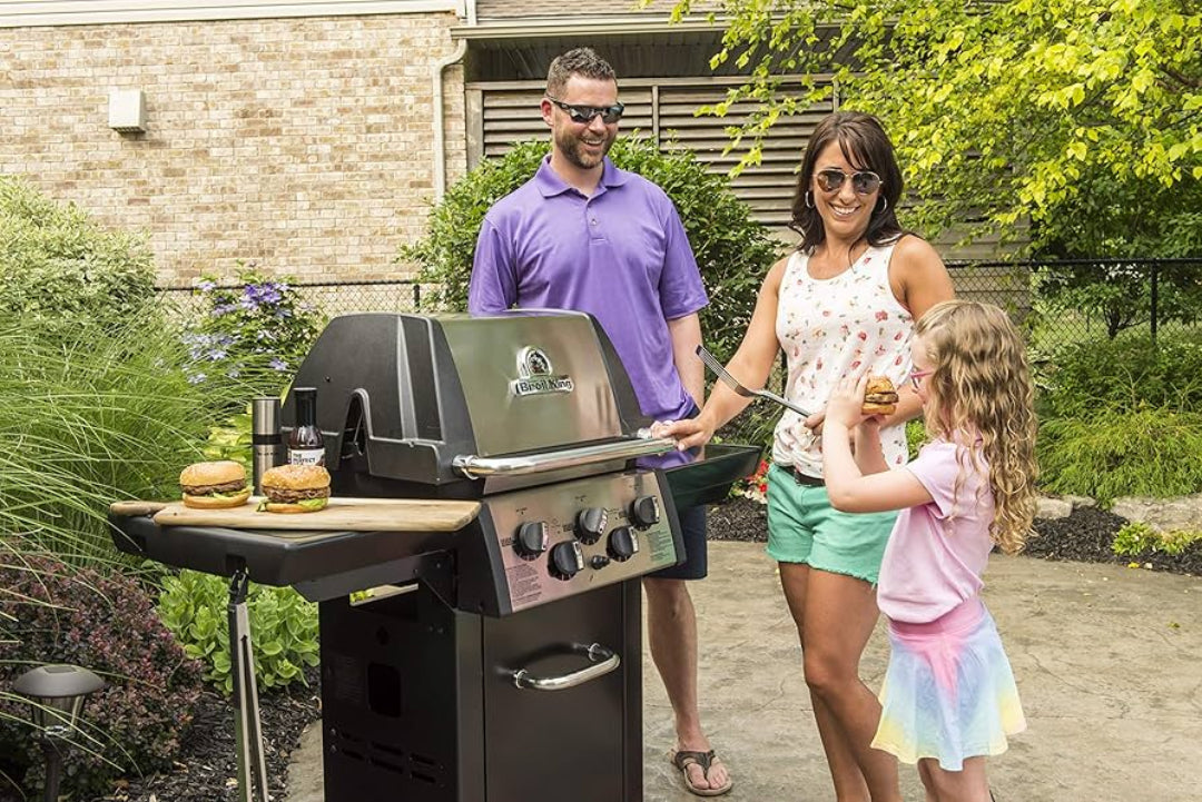 Freestanding Grill, Broil King, Baron Series, backyard family grilling scene with burgers and condiments on side shelf