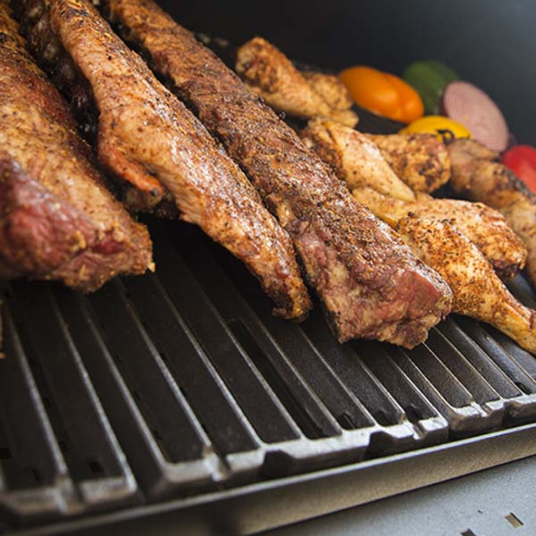 Cooking grates with food, Broil King, Smoke Series, cast iron cooking surface with ribs, chicken, and vegetables for even heat retention