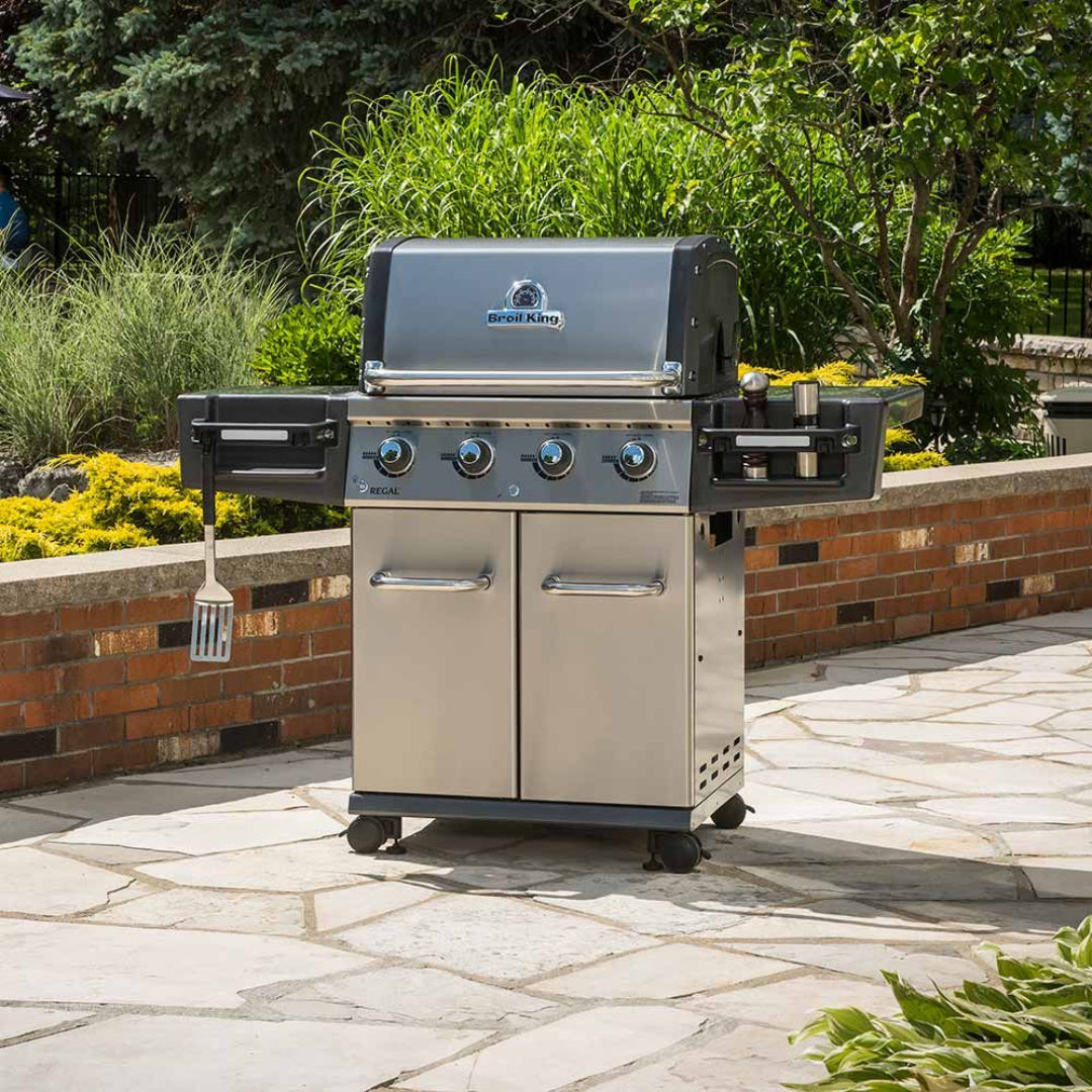 Broil King Regal S 420 stainless steel 4-burner propane grill with side burner, double-door storage cabinet and folding side shelves on patio