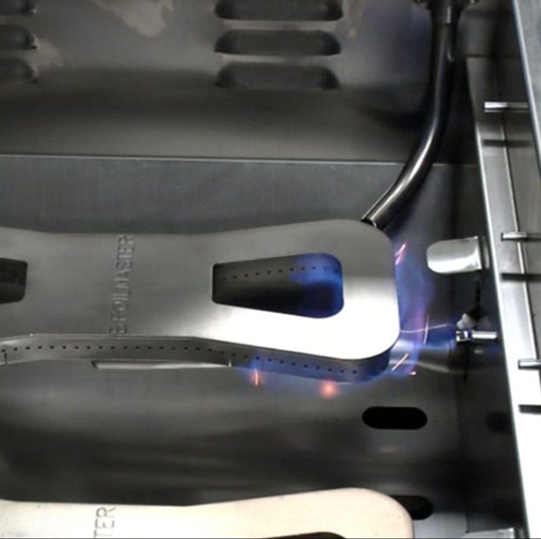 Broilmaster B-Series Basic Edition 3-burner 25-inch natural gas grill interior showing stainless steel flame tamer heat shield embossed BROILMASTER with lit blue burner flame model BSB253NLN5