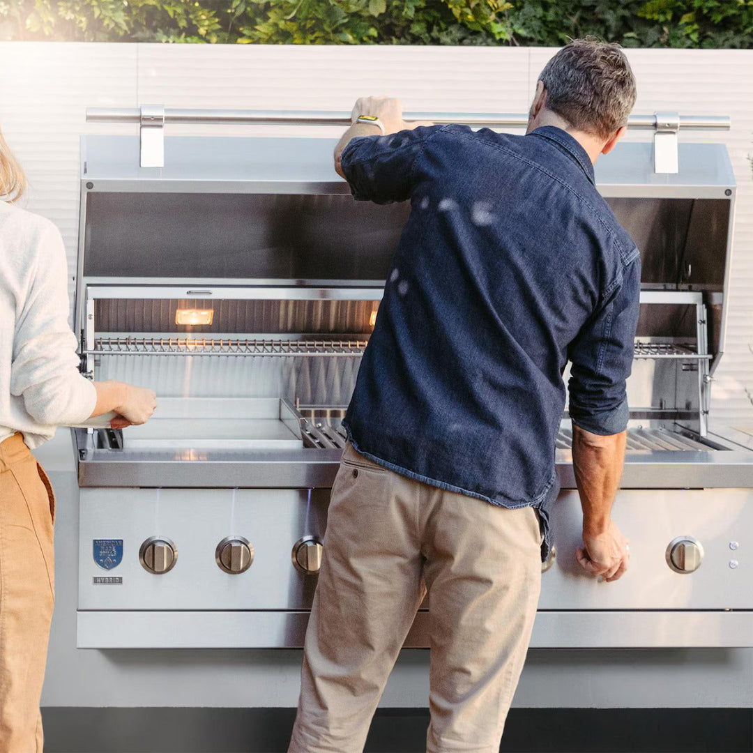 Man and woman opening American Made Grills Encore 36-inch propane grill with warming rack and internal lights