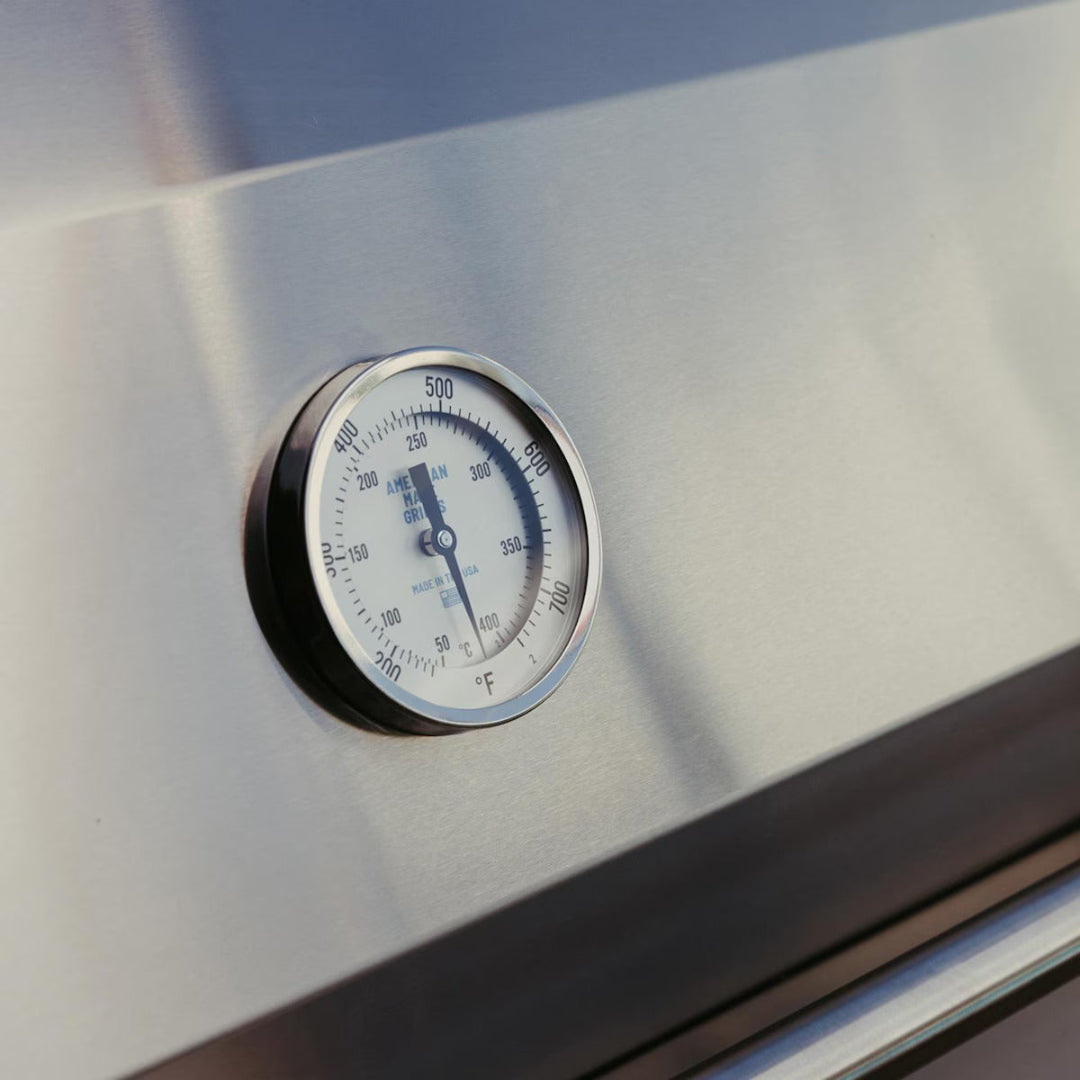 Close-up of built-in analog temperature gauge on hood of American Made Grills Encore 54" natural gas grill