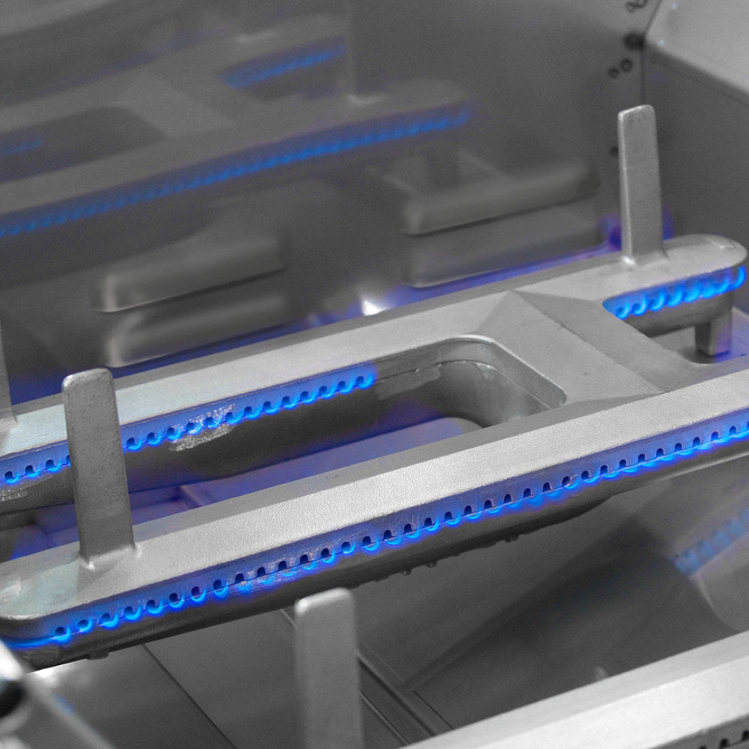 Echelon cast stainless steel E burner close-up showing blue gas flame ports under grill grates for outdoor kitchen gas grill