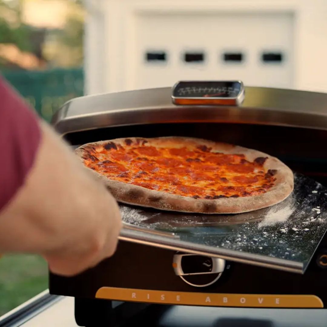 HALO Versa 16 Outdoor Gas Pizza Oven HZ-1004-ANA with 16" pizza on rotating cordierite stone being removed with a pizza peel