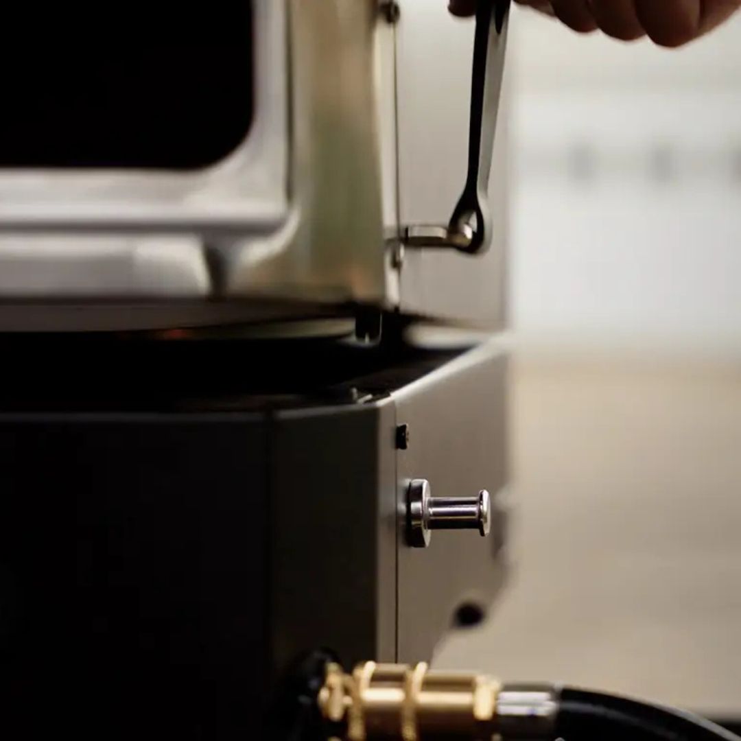 HALO Versa 16 (HZ-1004-ANA) outdoor gas pizza oven close-up showing hinged lid latch, 16-inch rotating cordierite stone and propane hose connection