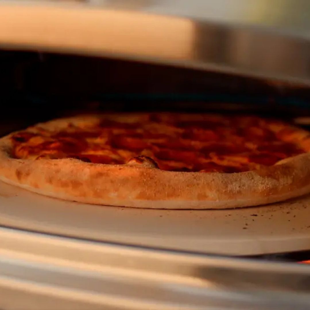 HALO Versa 16 (HZ-1004-ANA) outdoor gas pizza oven close-up of a 16-inch pizza baking on the rotating cordierite stone with a golden crust