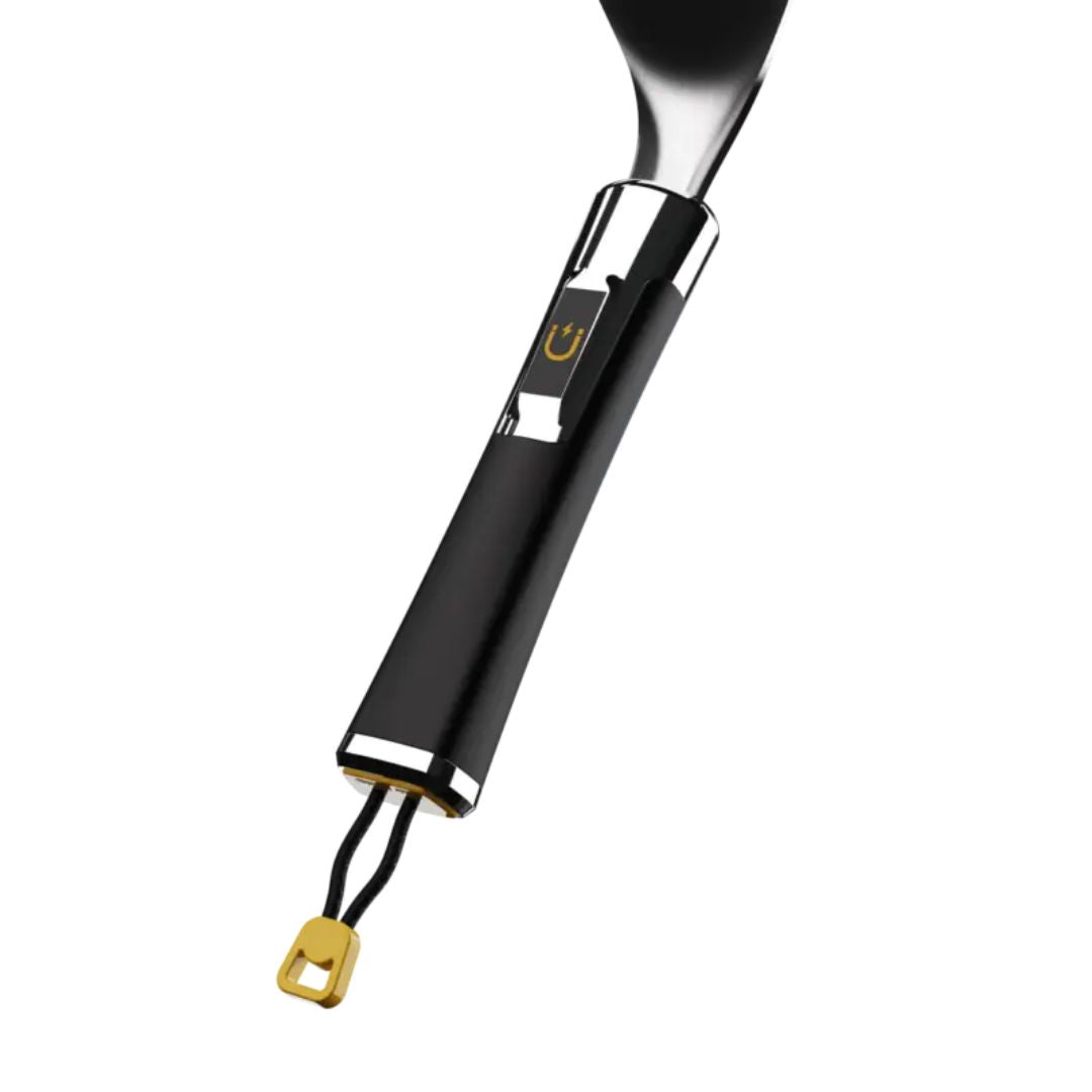 Close-up of HALO Elite griddle spatula handle — black magnetic stainless-steel handle with chrome ferrule, HALO magnet logo, and gold lanyard tag