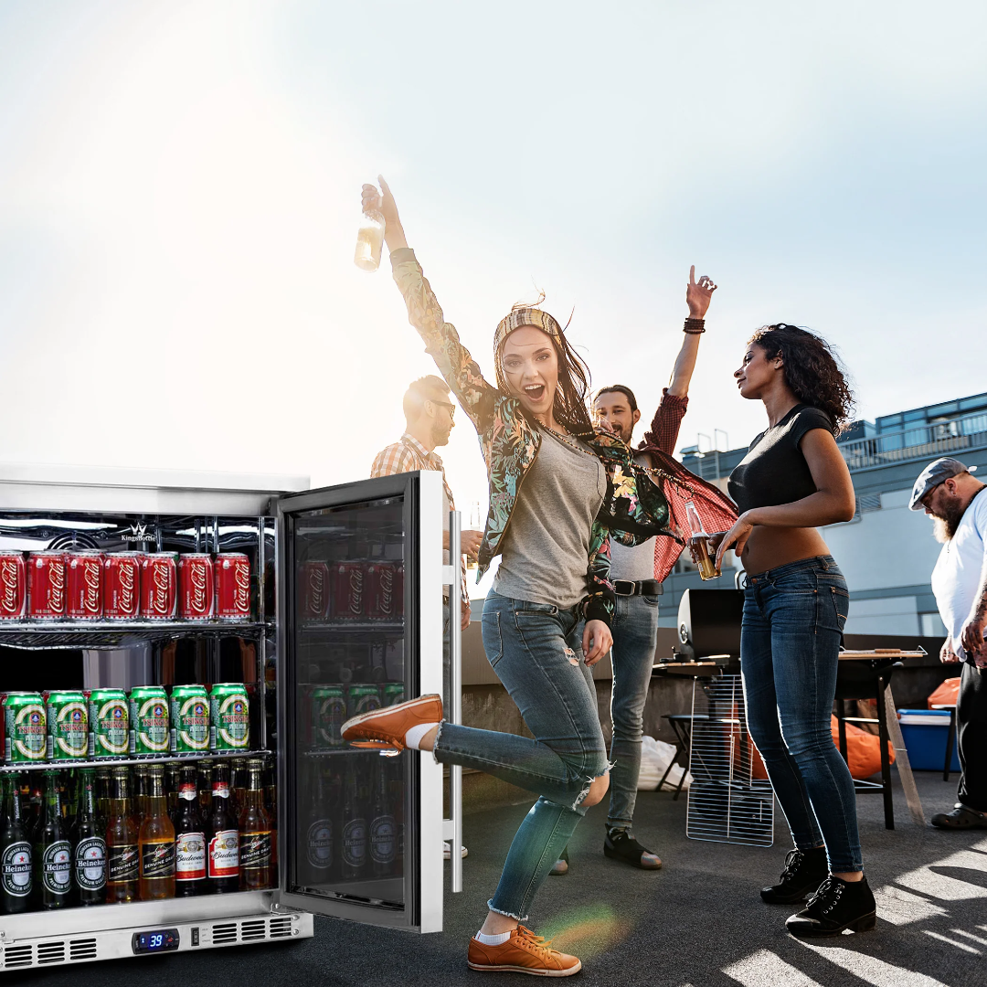 KBU55ASD stainless steel undercounter glass-door beverage refrigerator with digital temperature display, built-in outdoor bar fridge stocked with beer and soda at a rooftop party