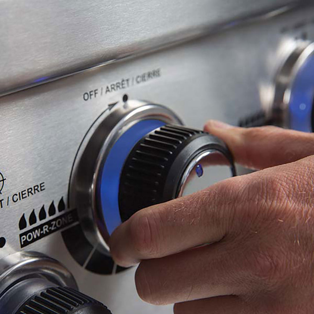 Close-up of hand adjusting blue LED backlit stainless steel control knob on Regal S 590 Pro infrared gas grill POW-R-ZONE