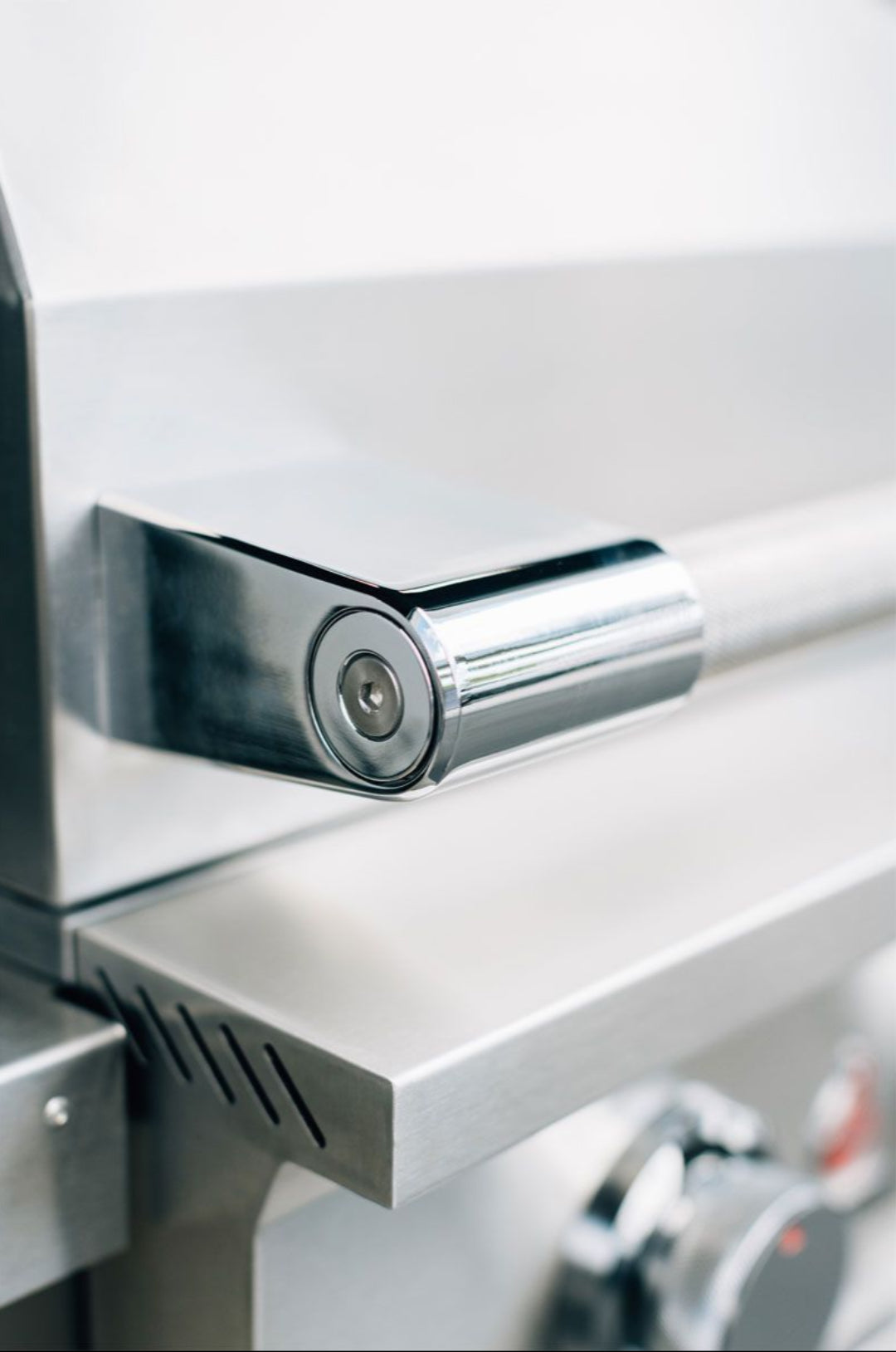 Close-up of stainless steel hood handle and hinge on True Flame TFE25-NG 3‑burner built‑in natural gas grill