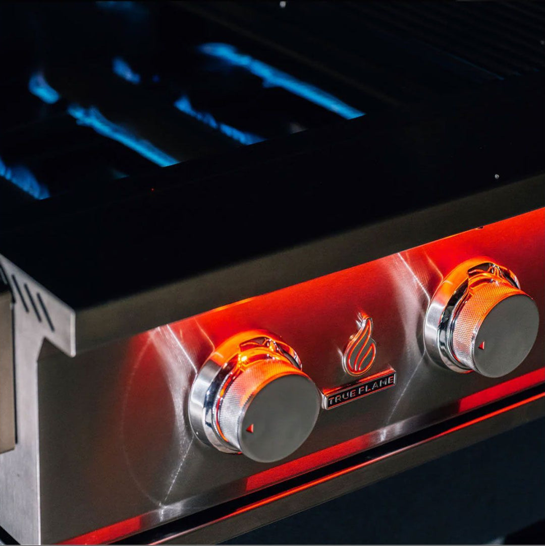True Flame TF25-NG 25‑inch 3‑burner built‑in natural gas grill stainless steel control panel close-up with illuminated knobs, True Flame logo and blue burner flames
